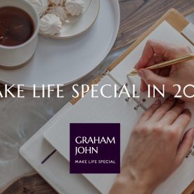 Hands writing in a notebook beside a cup of tea and festive treats, with text overlay “Make Life Special in 2026” and Graham John logo