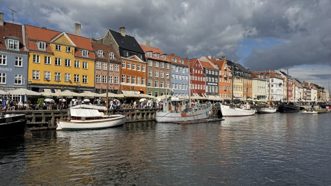 Nyhavn canal with colourful buildings and people sitting outdoors in summer